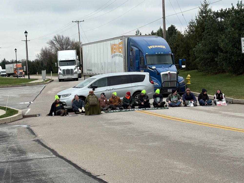 Starbucks workers in York PA sit down in the road, blocking a huge semi truck behind them